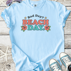 Light blue graphic tee with 'Bad Day? BEACH DAY!' text and floral design, perfect for summer outings.