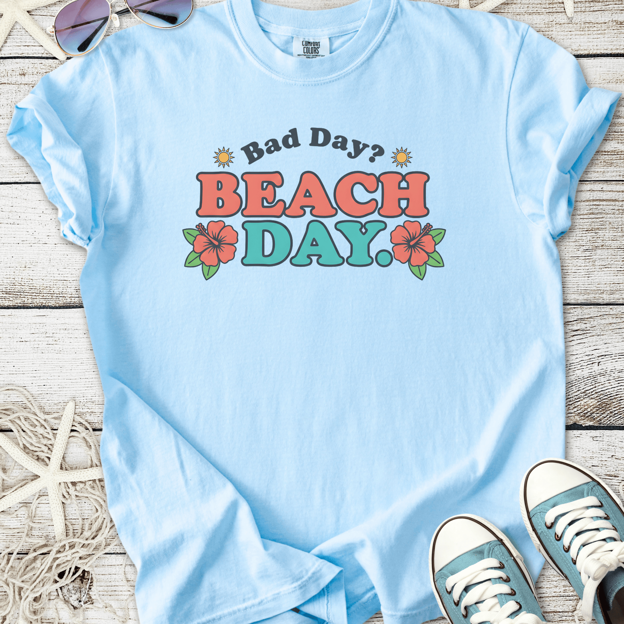 Light blue graphic tee with 'Bad Day? BEACH DAY!' text and floral design, perfect for summer outings.