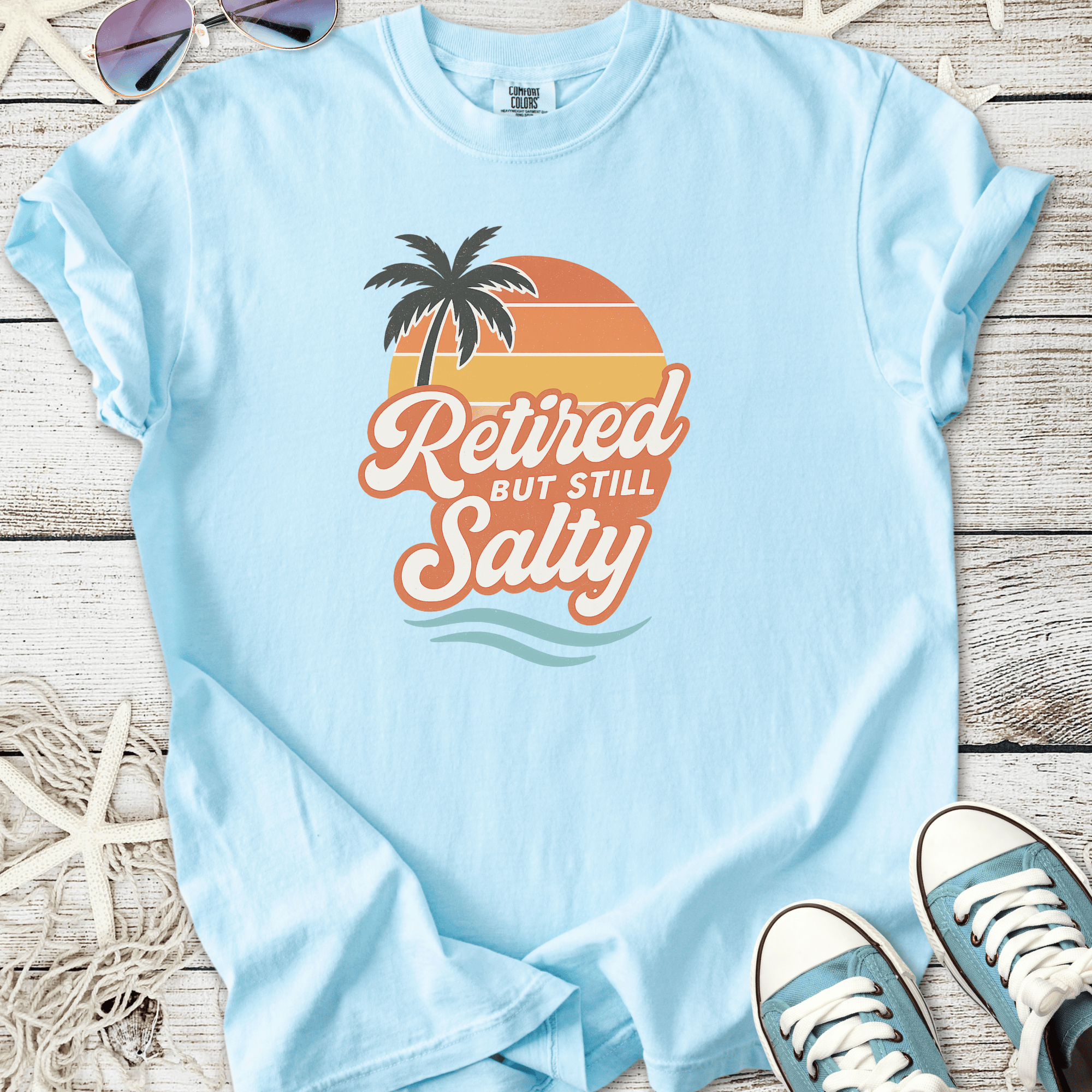 Light blue t-shirt with 'Retired But Still Salty' graphic, featuring palm tree and sunset design.