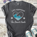 Dark gray unisex t-shirt with 'Life Happens, The Beach Heals' graphic and wave design.