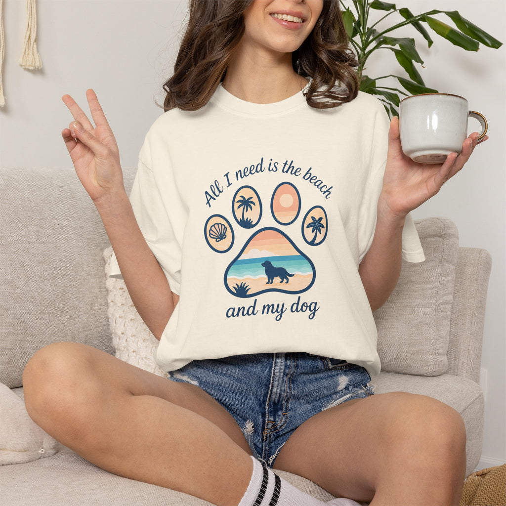 Cream graphic t-shirt with beach, dog, and palm tree design, perfect for casual wear.