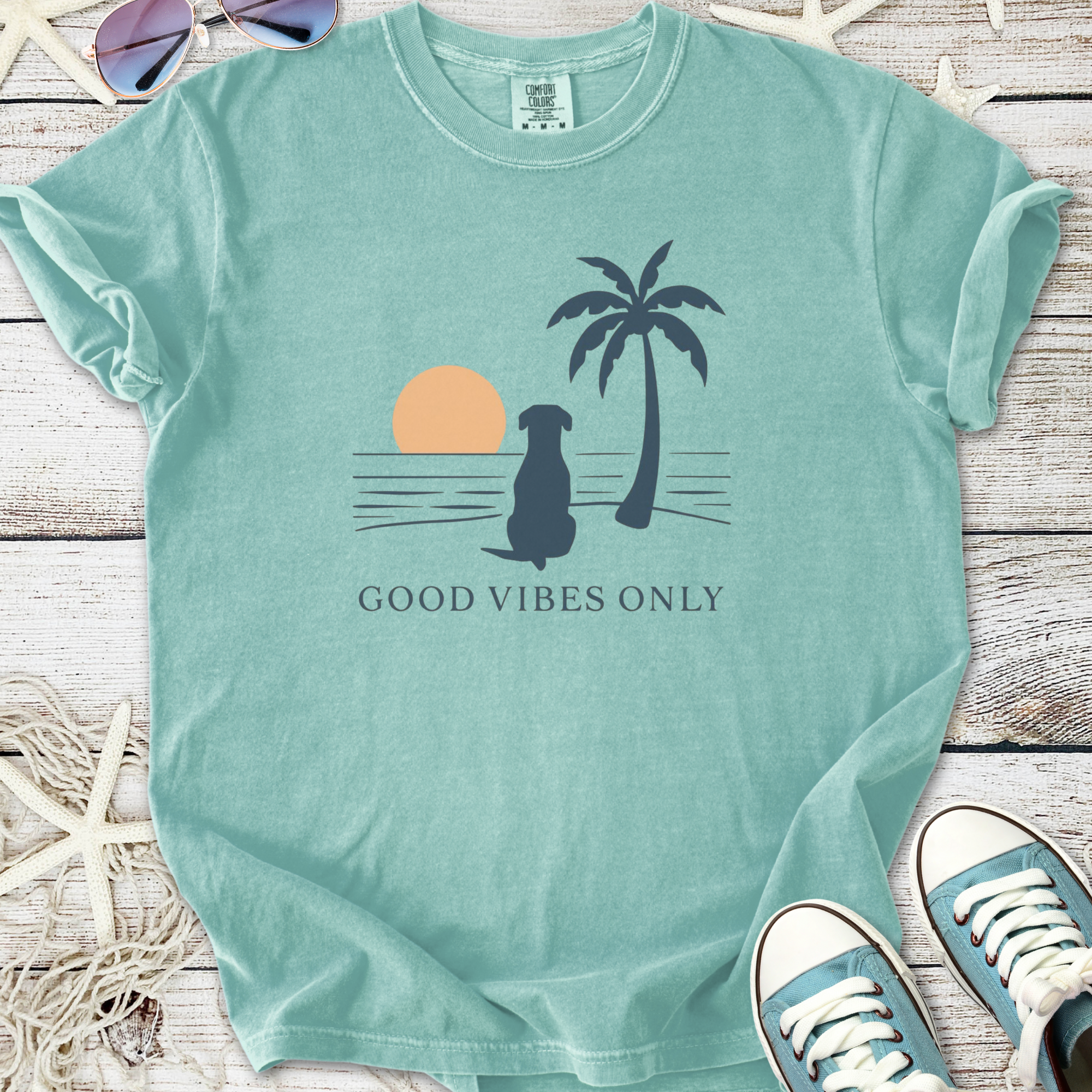 Mint green 'Good Vibes Only' t-shirt with dog, palm tree, and sunset graphic design.
