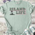 Mint green t-shirt with 'Island Life' graphic, featuring palm tree and house design, soft cotton material.