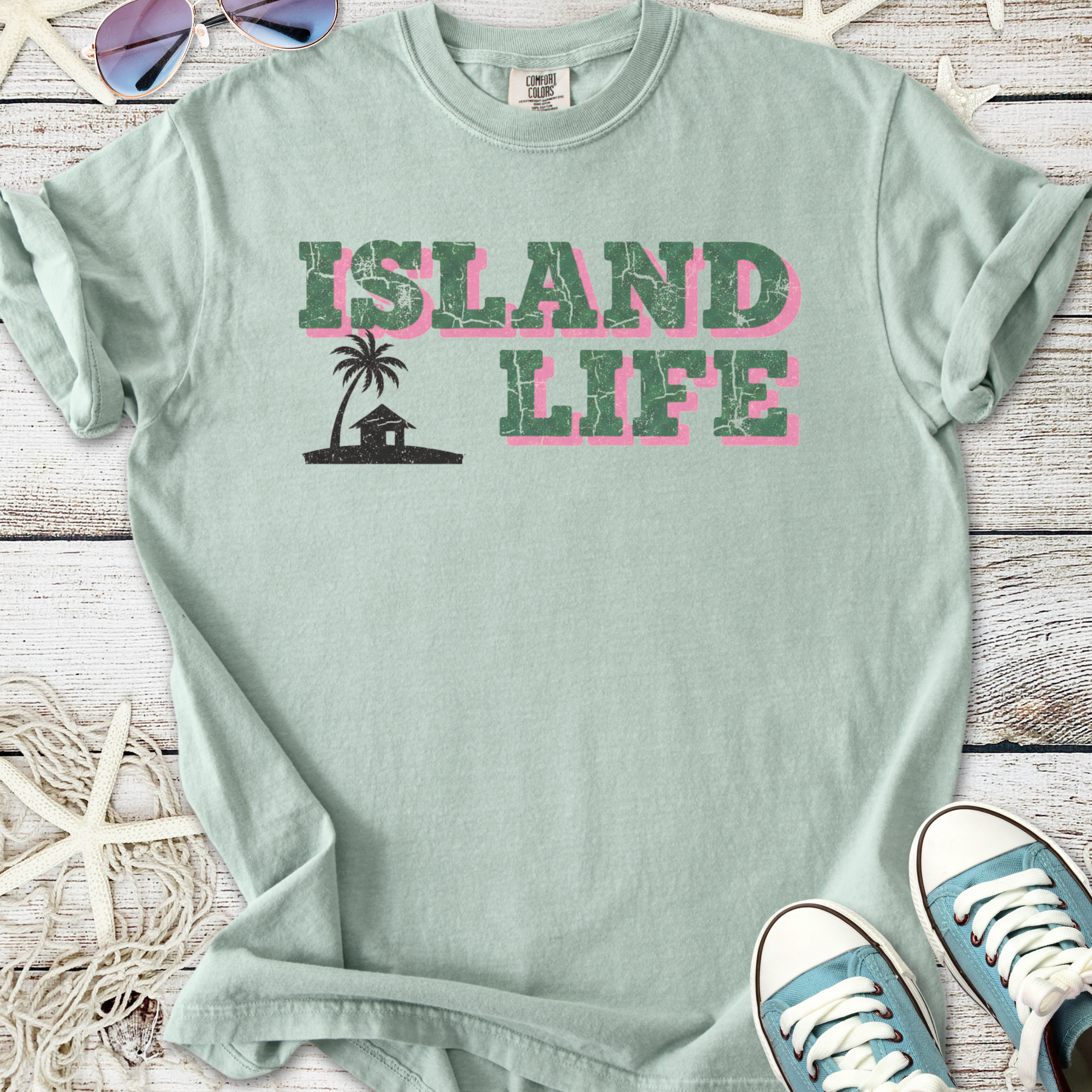 Mint green t-shirt with 'Island Life' graphic, featuring palm tree and house design, soft cotton material.