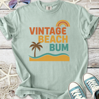Mint green vintage beach bum t-shirt, featuring palm tree and rainbow graphic design, perfect for summer outfits.