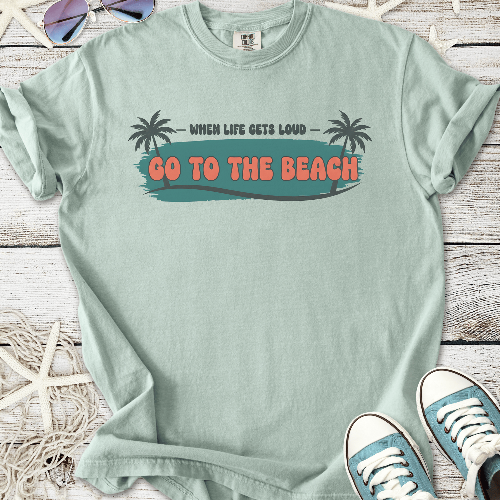 Mint green graphic t-shirt with 'Go to the Beach' slogan and palm tree illustrations.