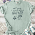 Light green graphic t-shirt featuring 'self care is spending time with my dog at the beach' text.
