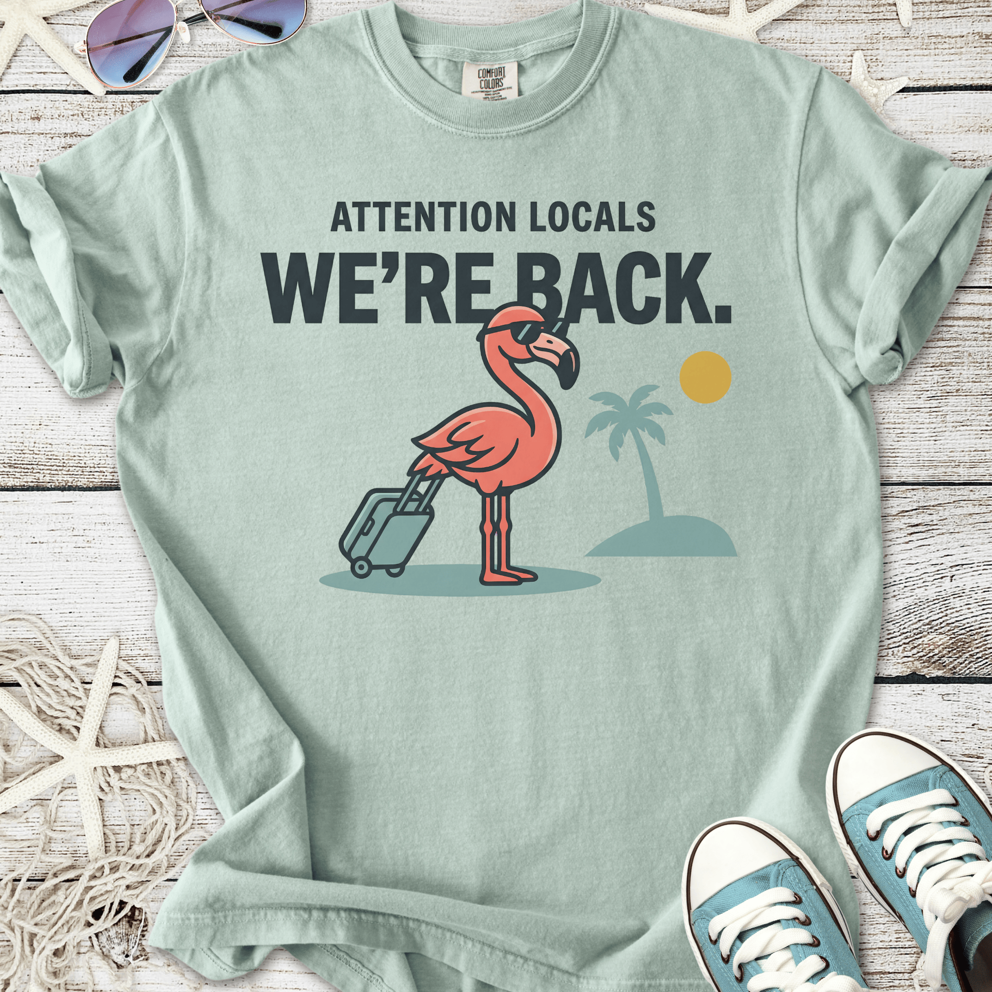 Mint green t-shirt featuring a flamingo with a suitcase and tropical design, ideal for casual wear.