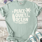 Mint green t-shirt featuring 'Peace Quiet Ocean' graphic, surfboard and palm trees, made of soft cotton.