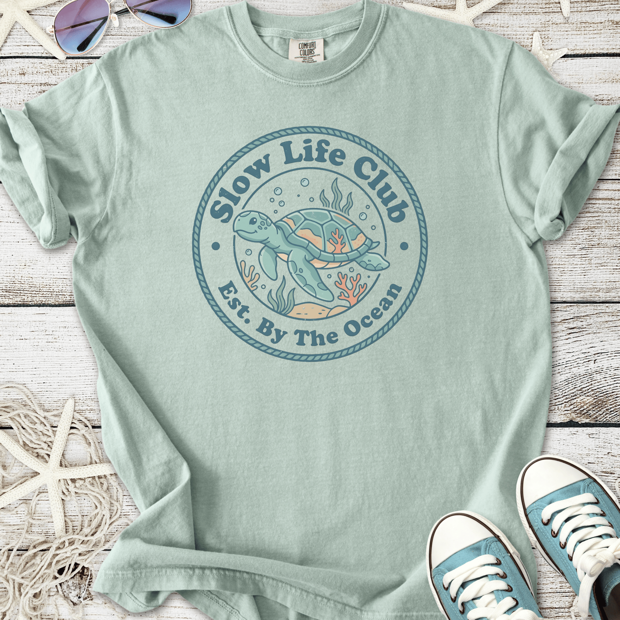 Mint green t-shirt featuring a turtle graphic for 'Slow Life Club', perfect for beach lovers.