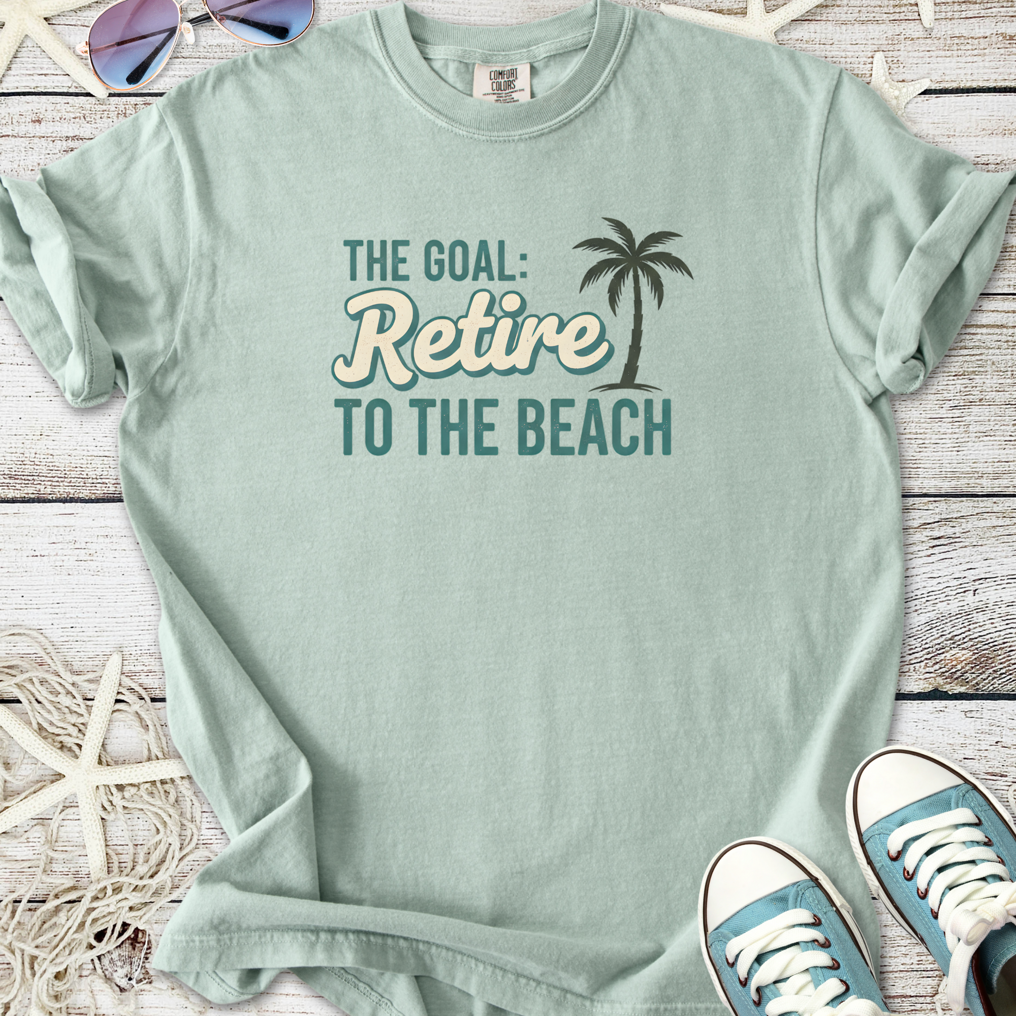 Mint green t-shirt with 'The Goal: Retire to the Beach' graphic, perfect for casual beach lovers.