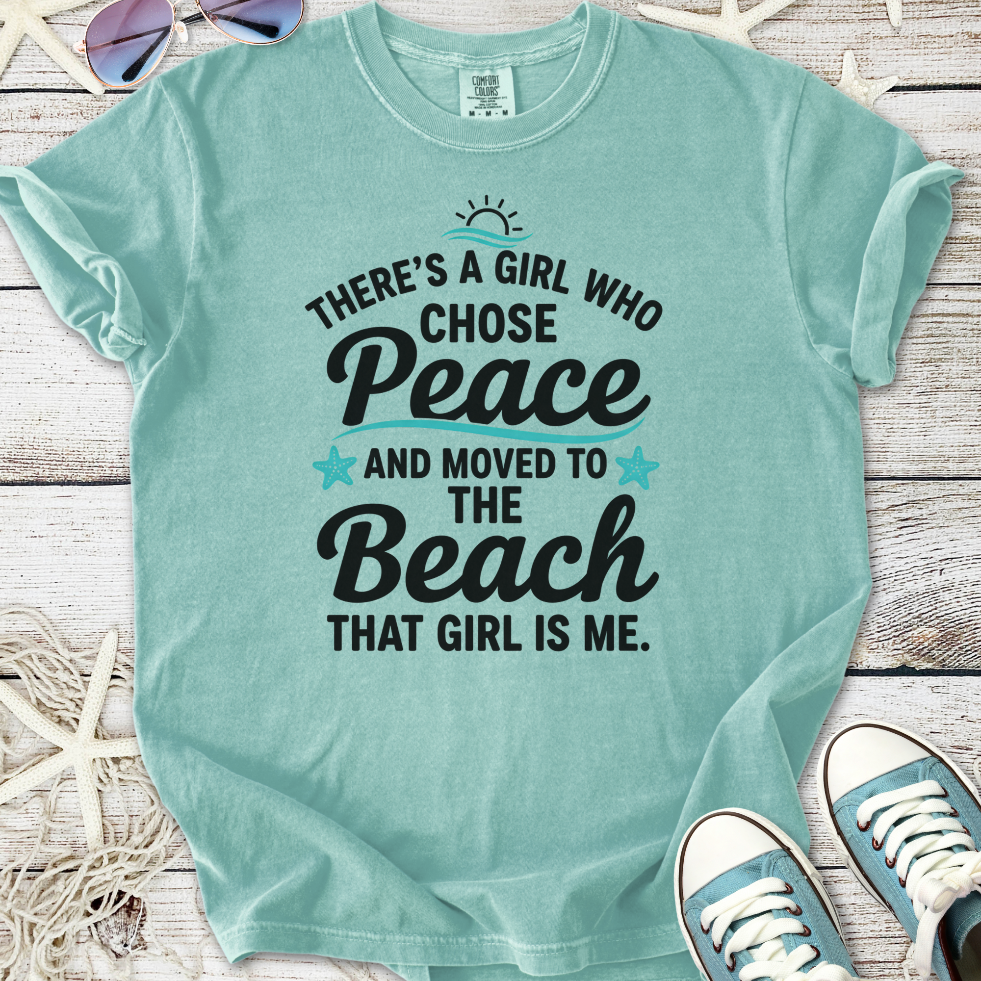 Mint green t-shirt with beach-themed graphic: 'There's a girl who chose peace and moved to the beach.'