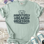 Light green t-shirt with 'Pawsitively Beach Obsessed' print, perfect for dog lovers and beach days.