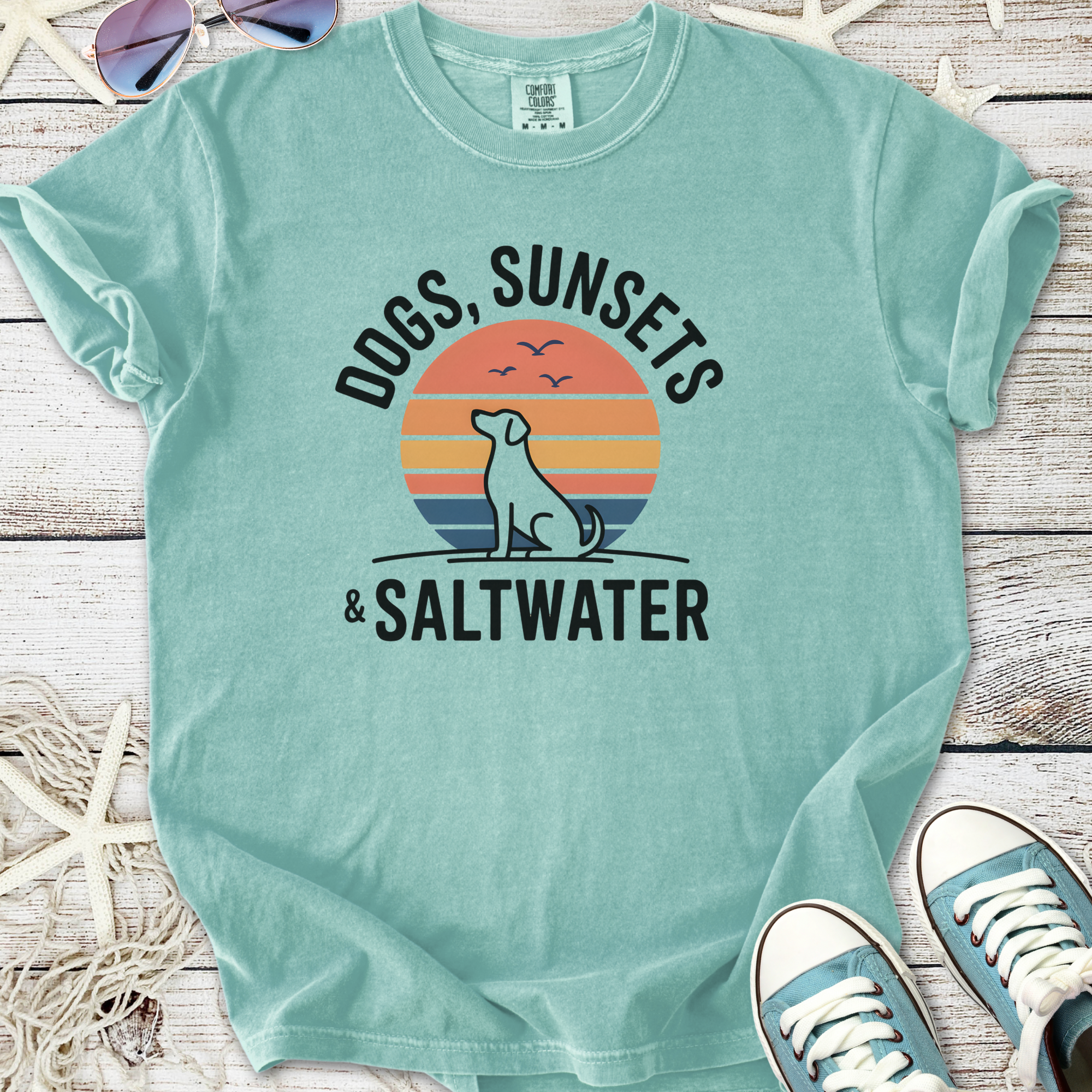 Teal cotton t-shirt featuring 'Dogs, Sunsets & Saltwater' graphic design, perfect for beach lovers.