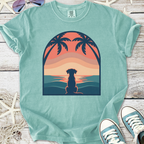 Turquoise graphic t-shirt featuring a dog silhouette at sunset with palm trees, made of soft cotton.