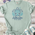Light green t-shirt with turtle design and 'Saltwater in My Veins' text, perfect for beach lovers.