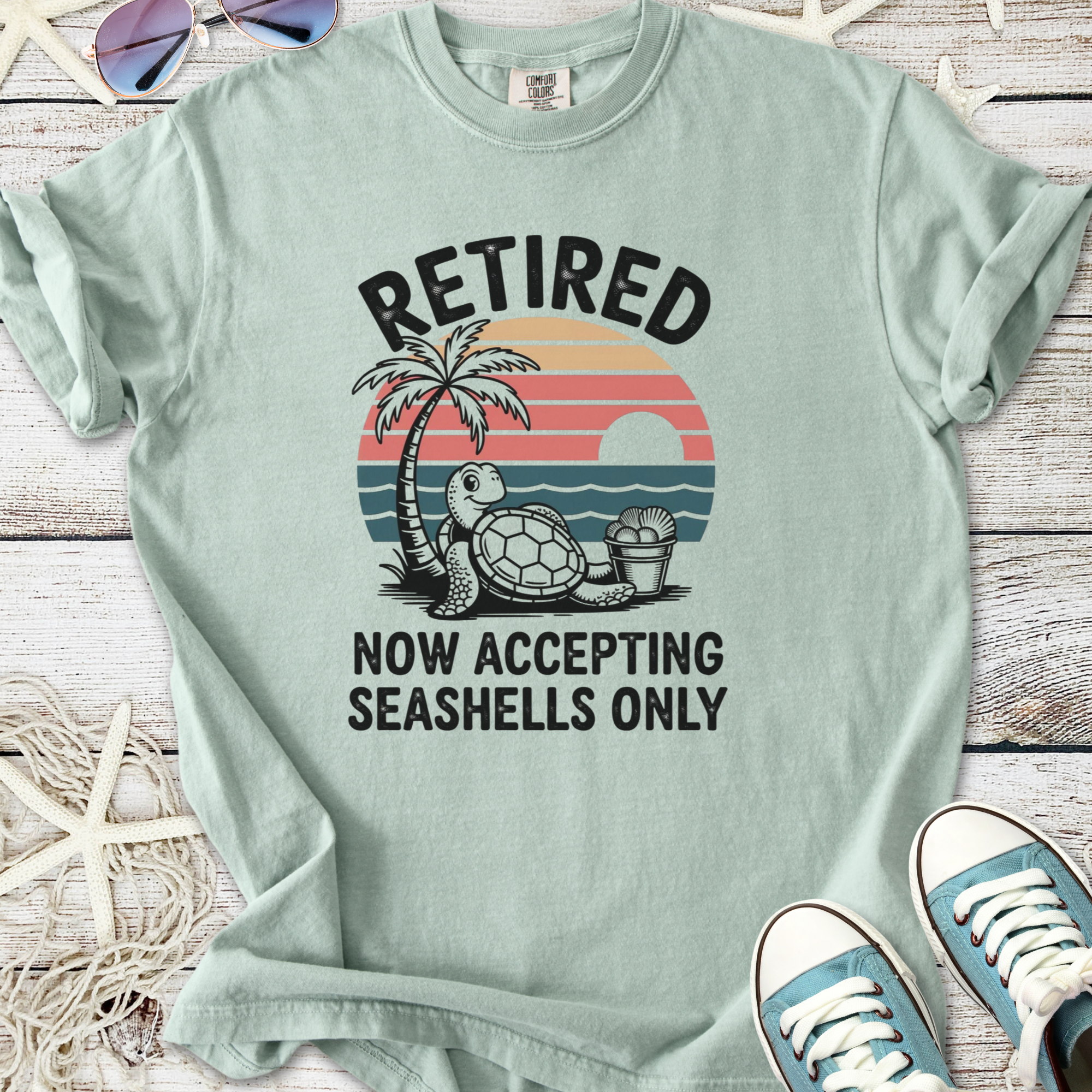 Light blue retirement-themed t-shirt with turtle and palm tree graphic, humorous seashell design.