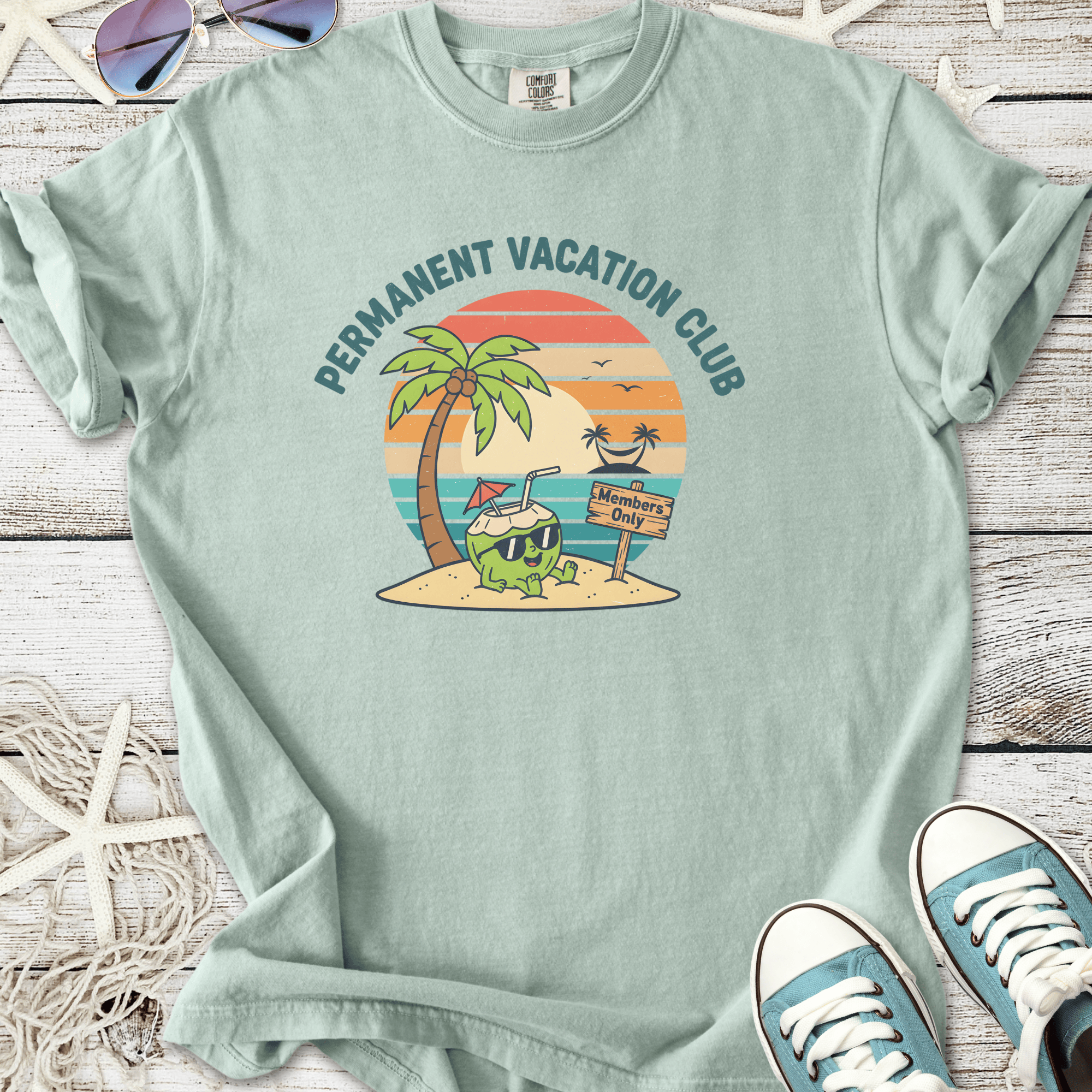 Light blue t-shirt featuring 'Permanent Vacation Club' graphic with a cartoon coconut drink and palm trees.