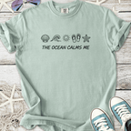 Light teal t-shirt with 'The Ocean Calms Me' print and beach-themed graphics. Comfortable cotton material.
