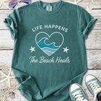 Teal beach-themed t-shirt with 'Life Happens The Beach Heals' graphic and starfish design.