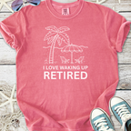Pink cotton t-shirt design with 'I Love Waking Up Retired' and beach graphics, perfect for retirees.