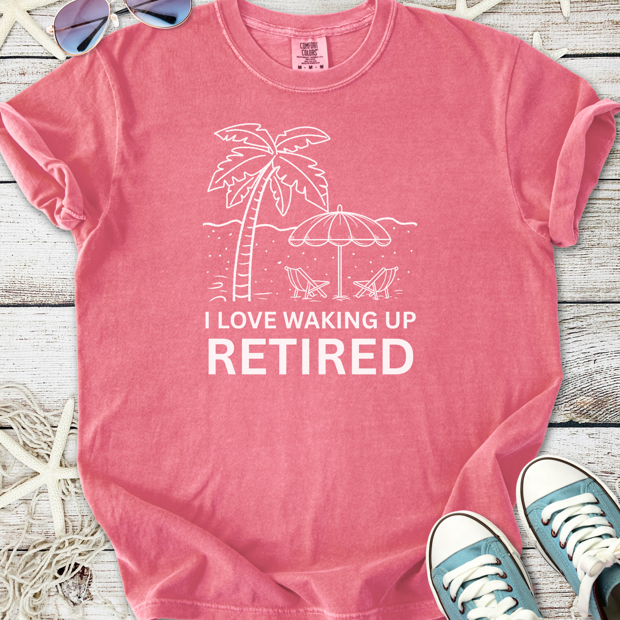 Pink cotton t-shirt design with 'I Love Waking Up Retired' and beach graphics, perfect for retirees.