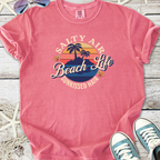 Pink graphic t-shirt featuring 'Salty Air Beach Life' design, soft cotton material, perfect for beach lovers.