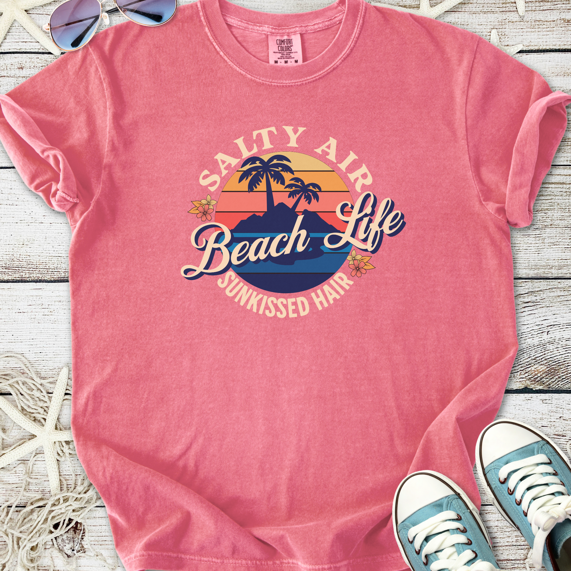 Pink graphic t-shirt featuring 'Salty Air Beach Life' design, soft cotton material, perfect for beach lovers.