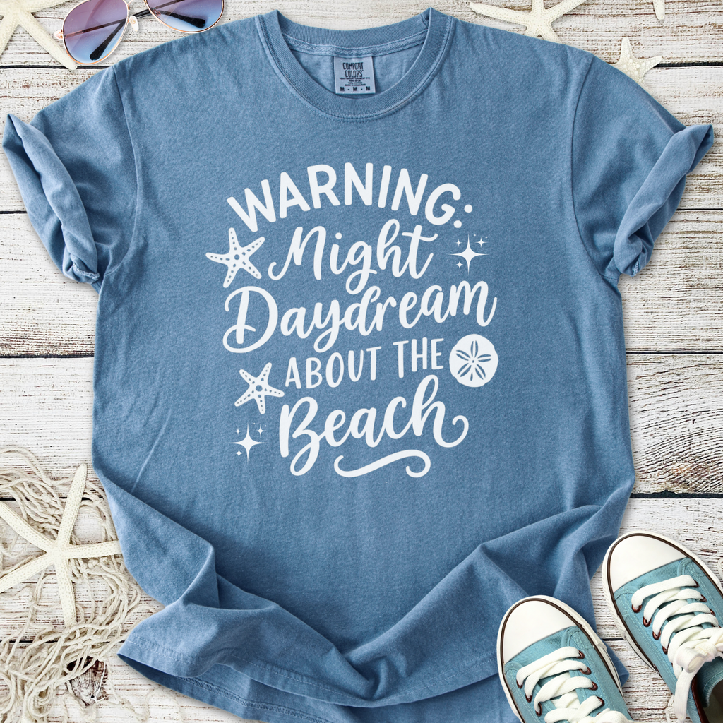 Light blue unisex t-shirt with beach-themed graphic warning about daydreaming.