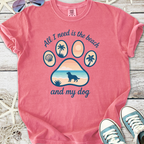 Pink graphic tee featuring beach-themed design with paw print, saying 'All I need is the beach and my dog'.