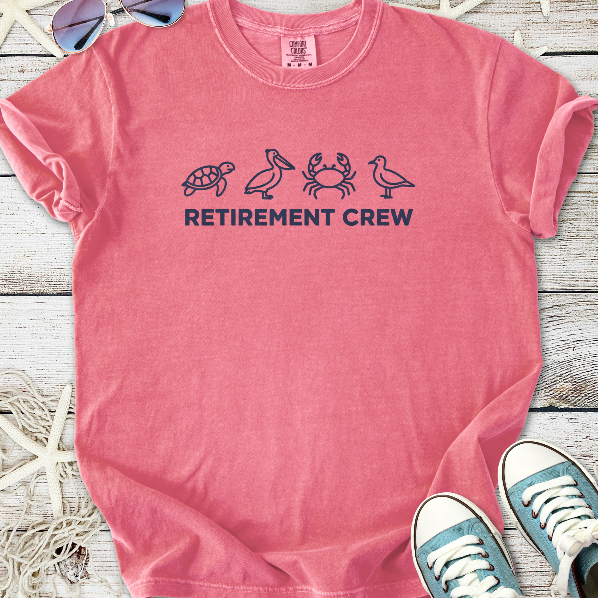 Pink cotton t-shirt with 'Retirement Crew' graphic and beach-themed icons, perfect for relaxed outings.