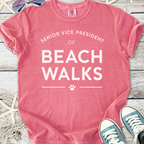 Pink cotton t-shirt with 'Senior Vice President of Beach Walks' slogan, perfect for casual beach outings.