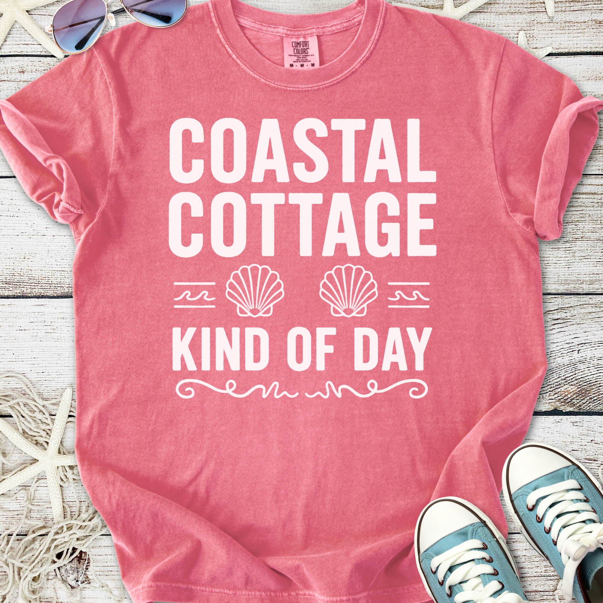 Pink 'Coastal Cottage Kind of Day' graphic t-shirt made of soft cotton, styled with sunglasses and sneakers.