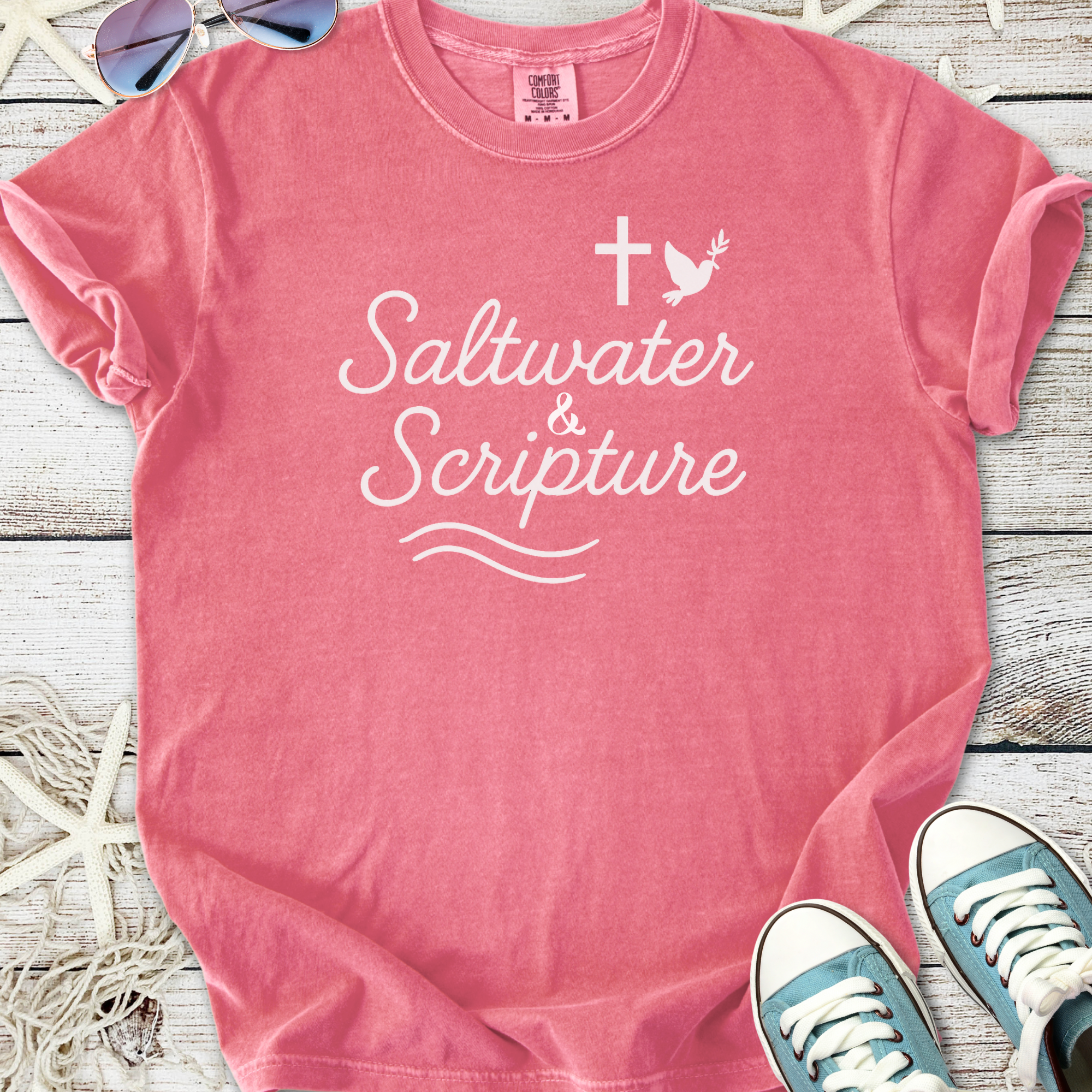 Pink cotton t-shirt featuring 'Saltwater & Scripture' design with cross and dove motifs.