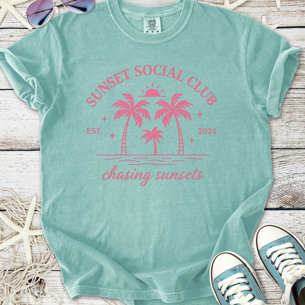 Mint green t-shirt with pink 'Sunset Social Club' graphic and palm trees, perfect for summer vibes.