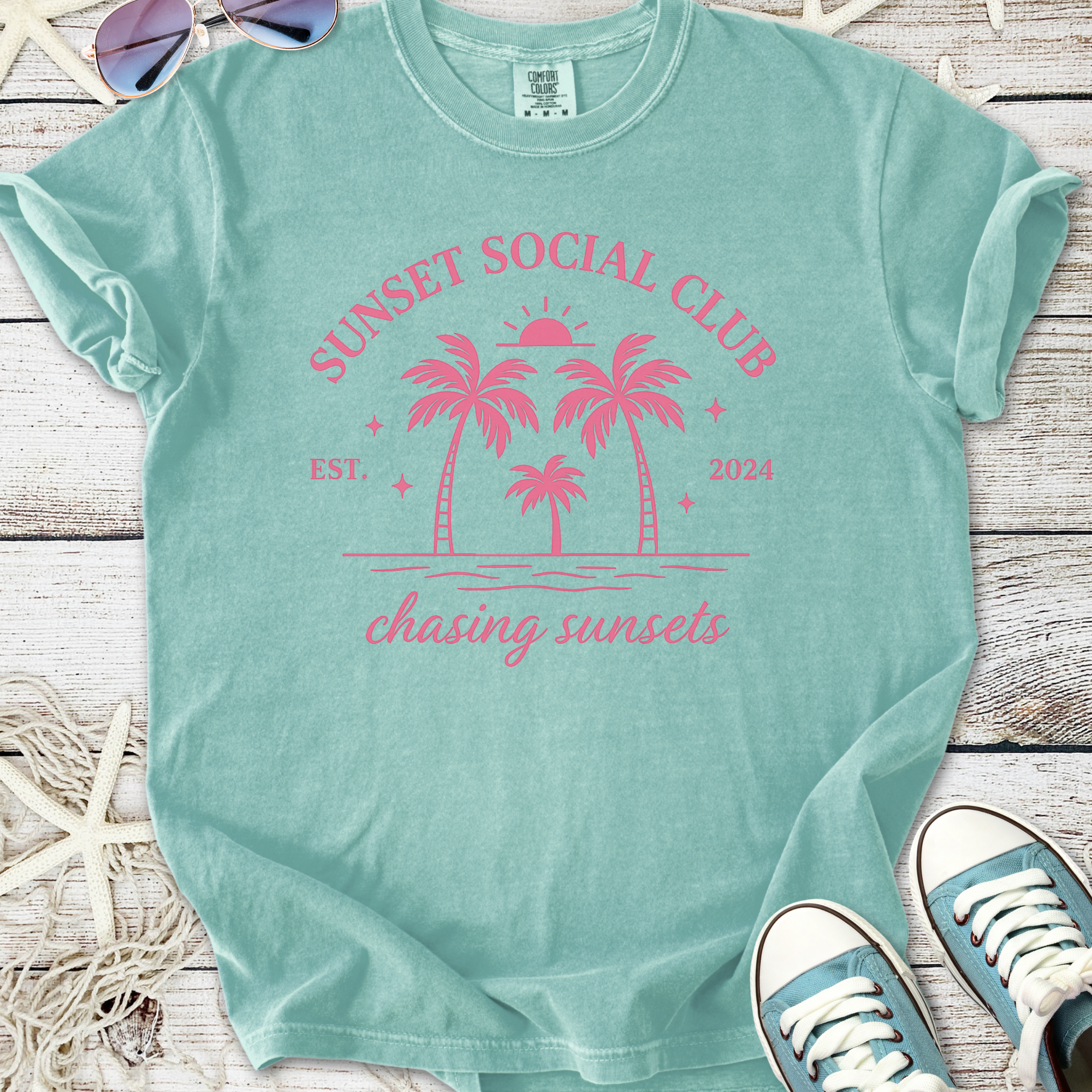 Mint green t-shirt with pink 'Sunset Social Club' graphic and palm trees, perfect for summer vibes.