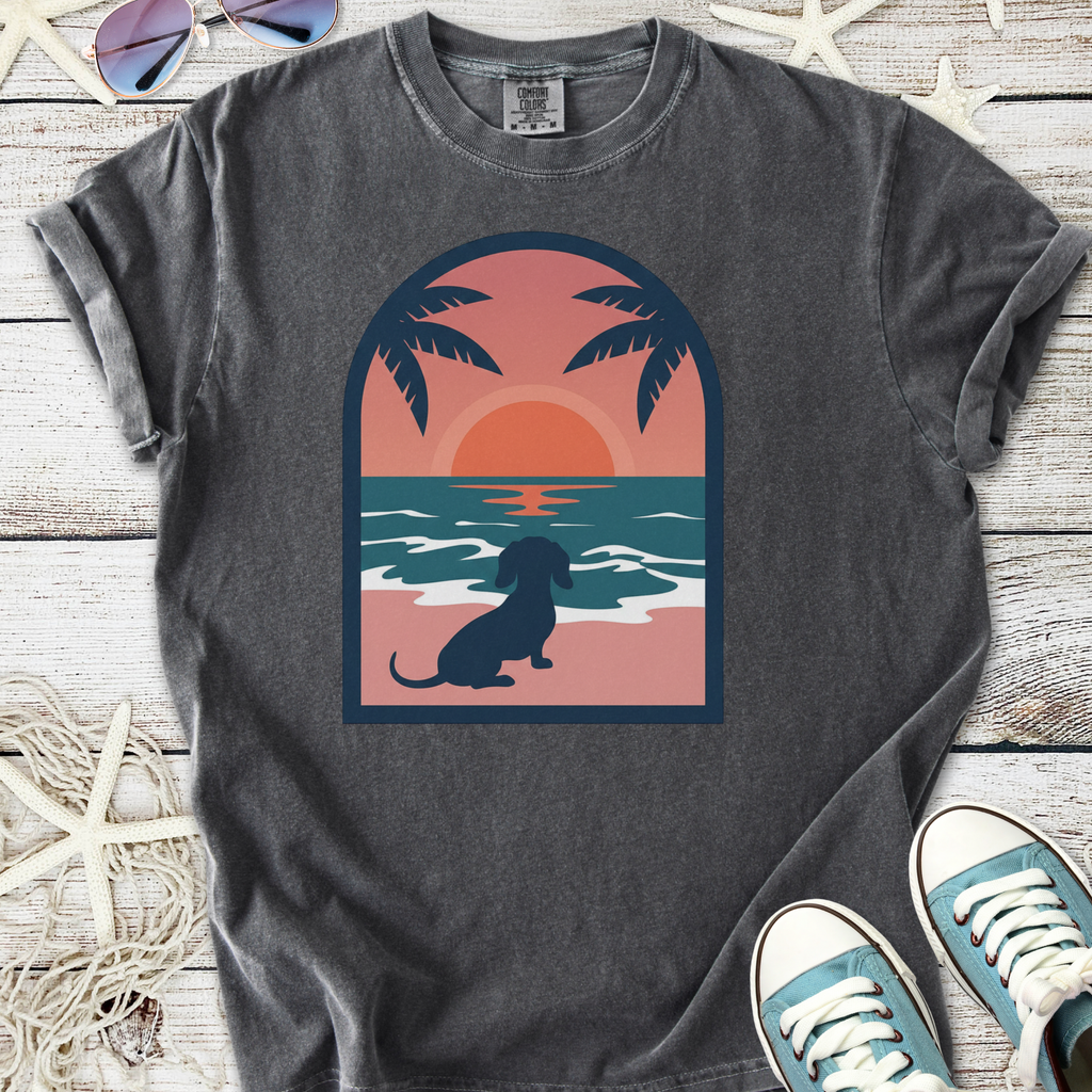 Gray graphic t-shirt featuring a dachshund by the beach at sunset, perfect for dog lovers.