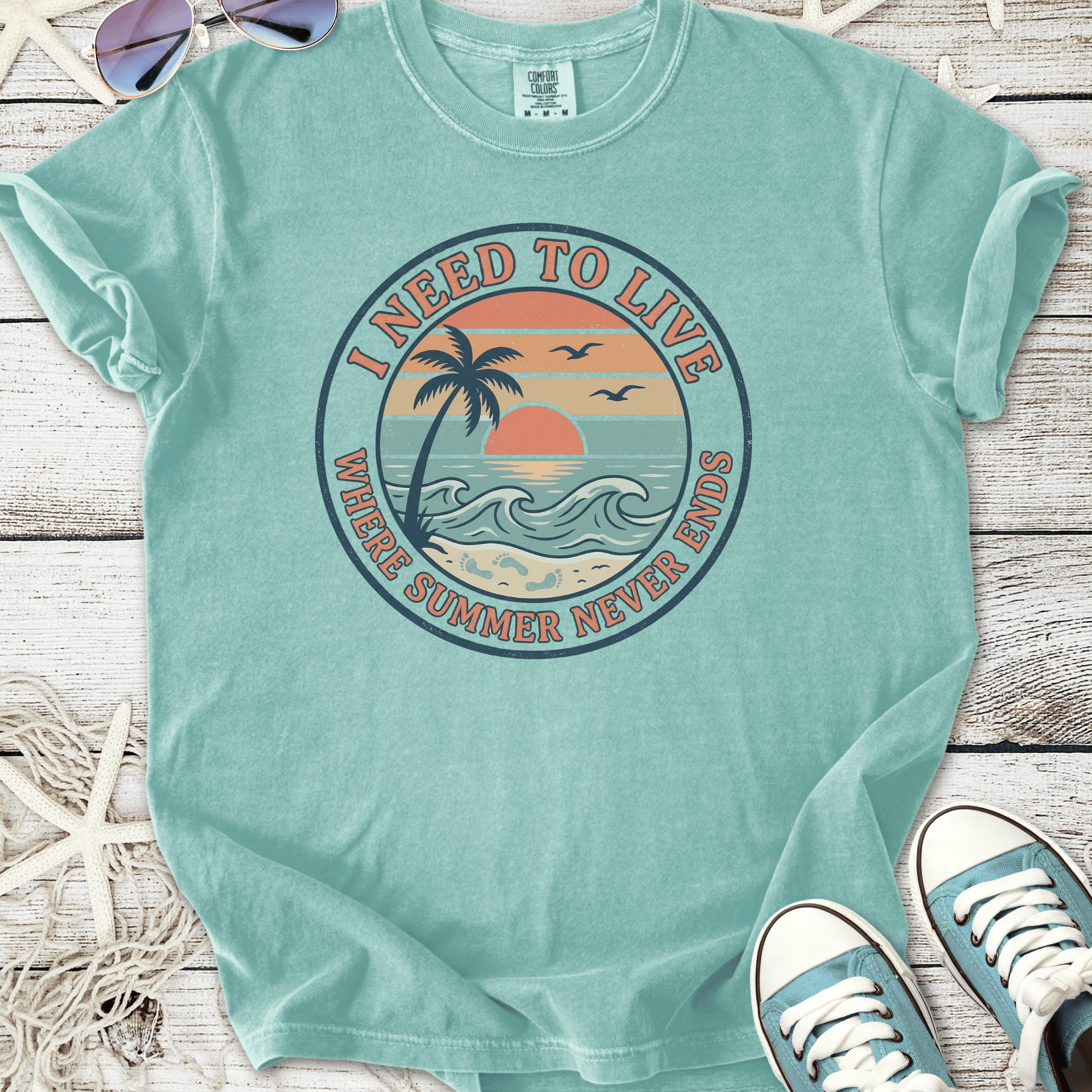 Mint green t-shirt featuring 'I Need to Live' beach graphic, perfect for summer vibes.