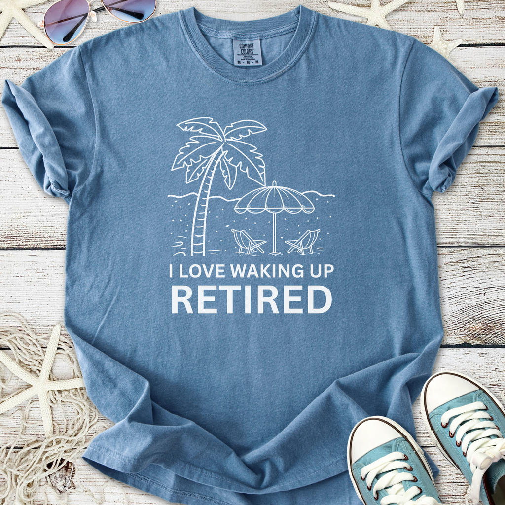 Blue cotton t-shirt with 'I Love Waking Up Retired' graphic, featuring palm trees and beach chairs.