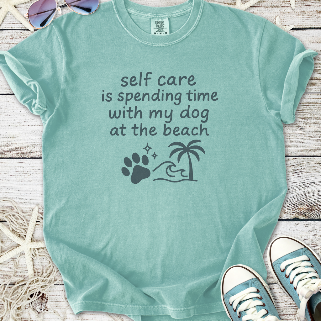 Light teal t-shirt with dog beach theme, saying 'self care is spending time with my dog at the beach'.