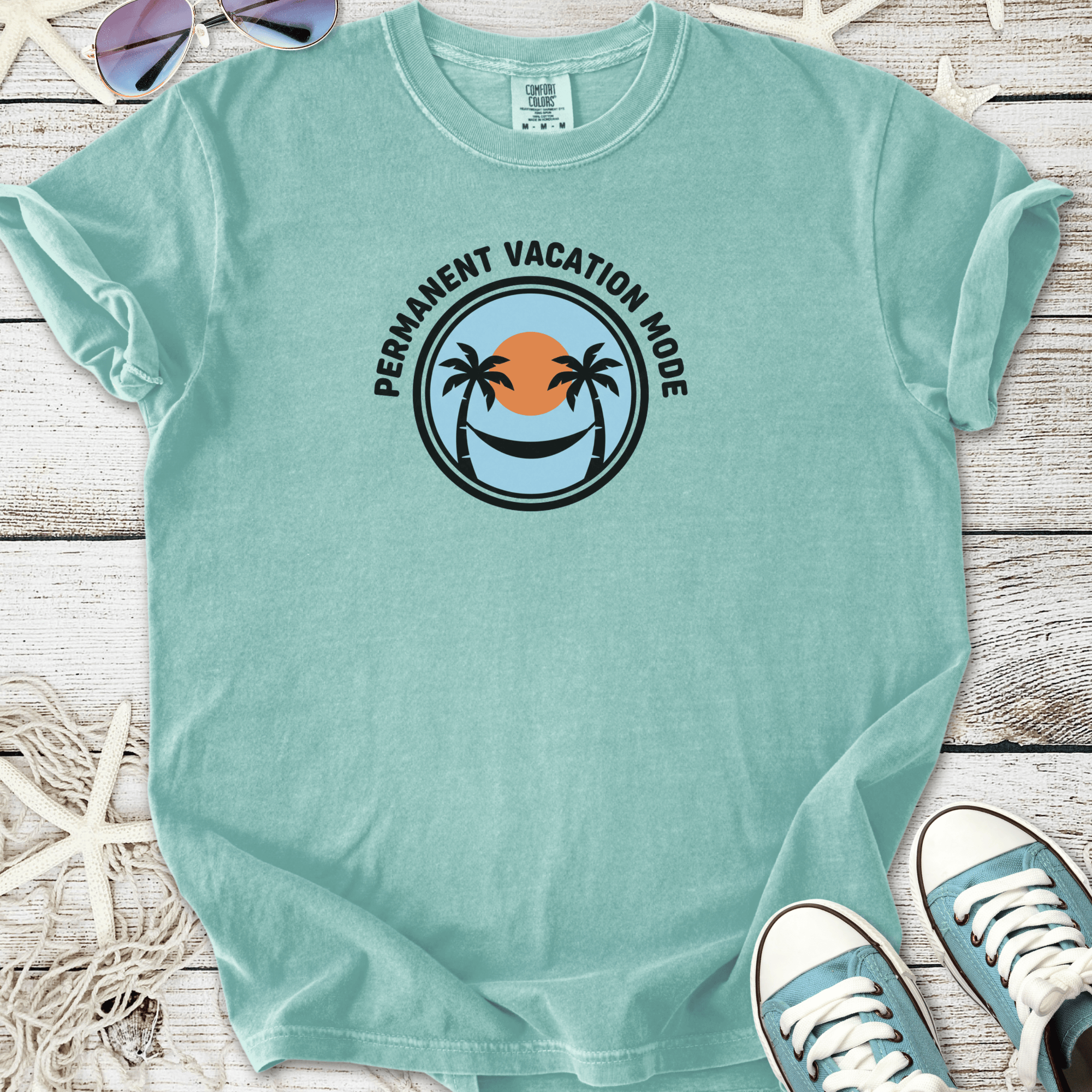 Mint green t-shirt with 'Permanent Vacation Mode' graphic, featuring palm trees and sunset design.