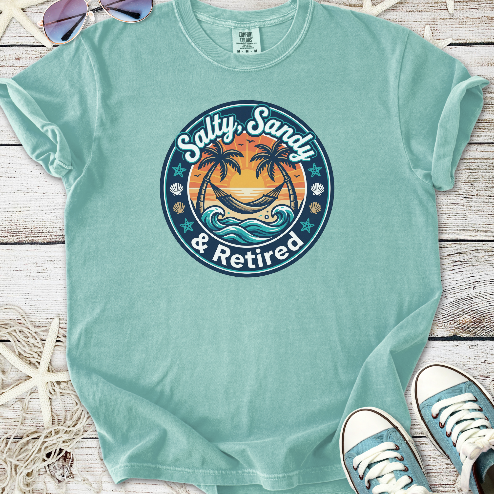 Light blue t-shirt featuring 'Salty, Sandy & Retired' graphic with palm trees and waves.