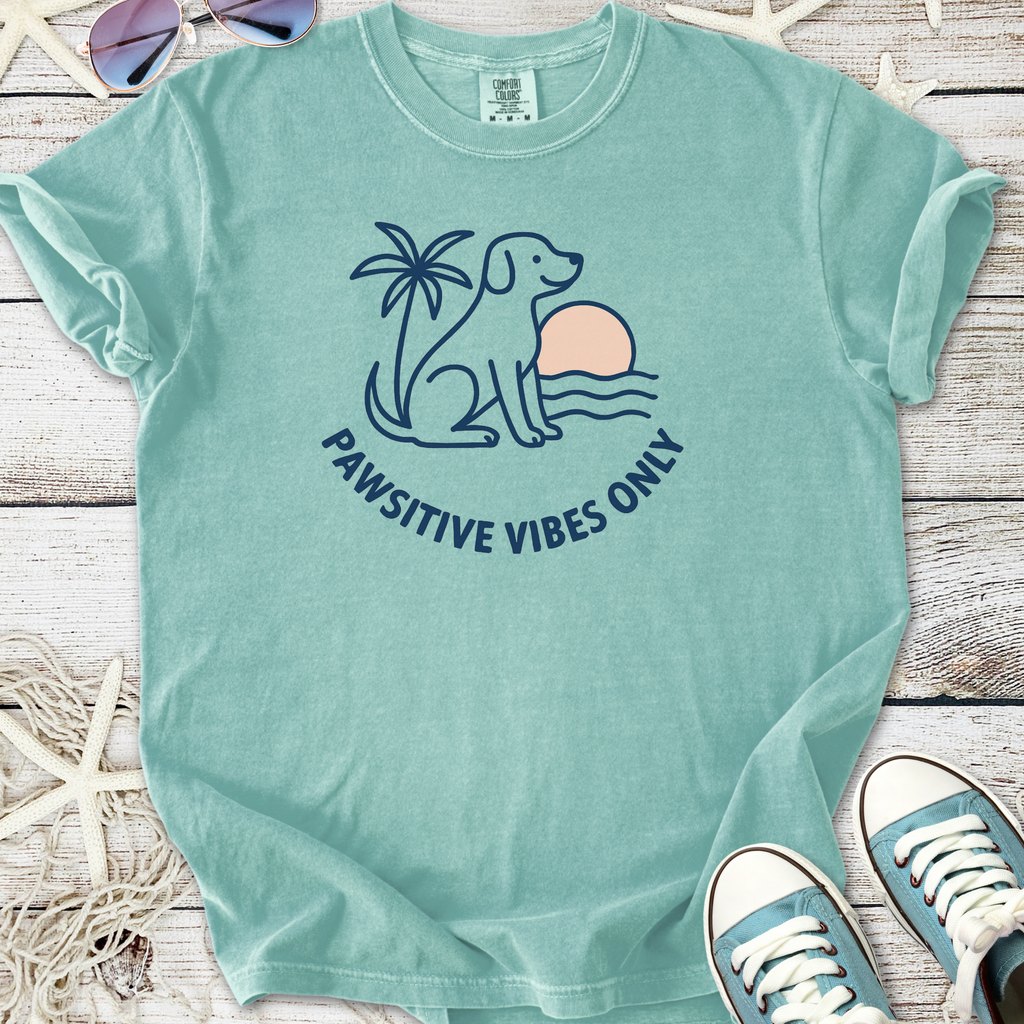 Mint green t-shirt featuring a dog, palm tree, and sunset with 'Pawsitive Vibes Only' slogan.
