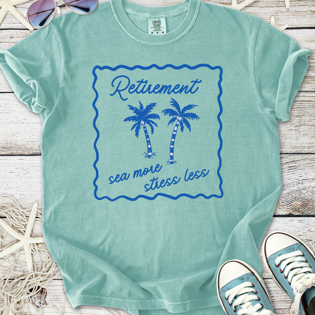 Light teal retirement t-shirt with palm tree design and 'sea more stress less' text.