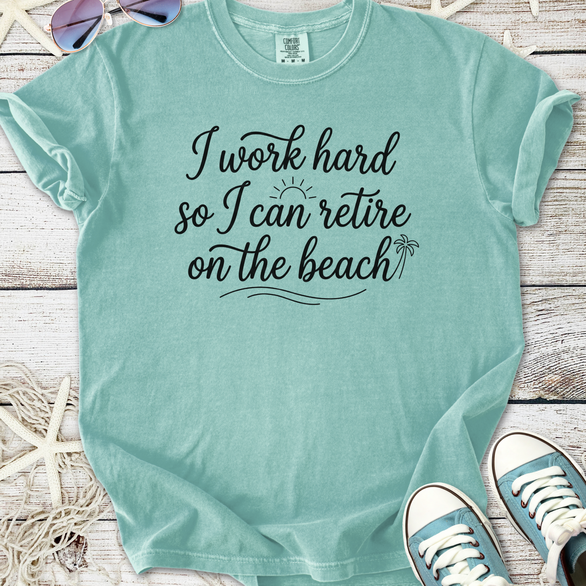 Mint green graphic tee with 'I work hard so I can retire on the beach' slogan, casual style, soft cotton.
