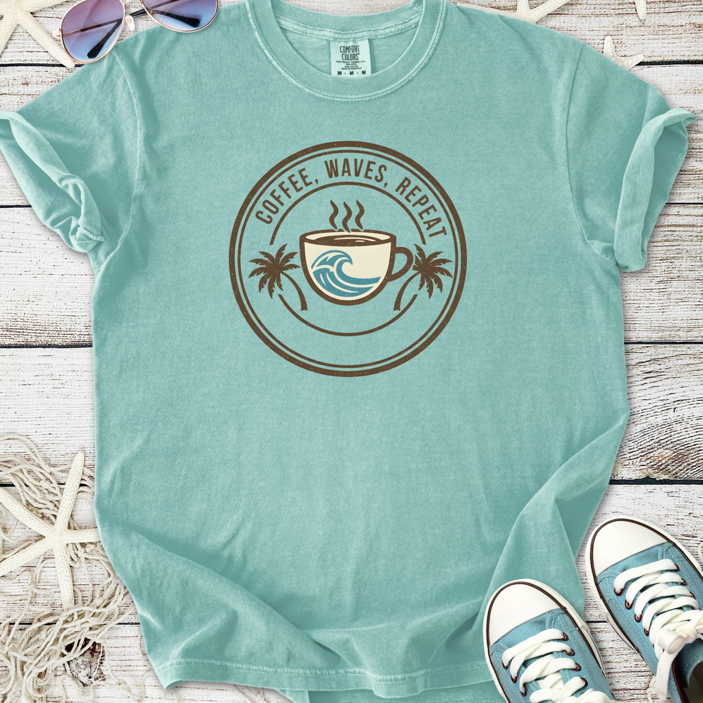 Light blue t-shirt with 'Coffee, Waves, Repeat' graphic, made from soft cotton for casual beach wear.