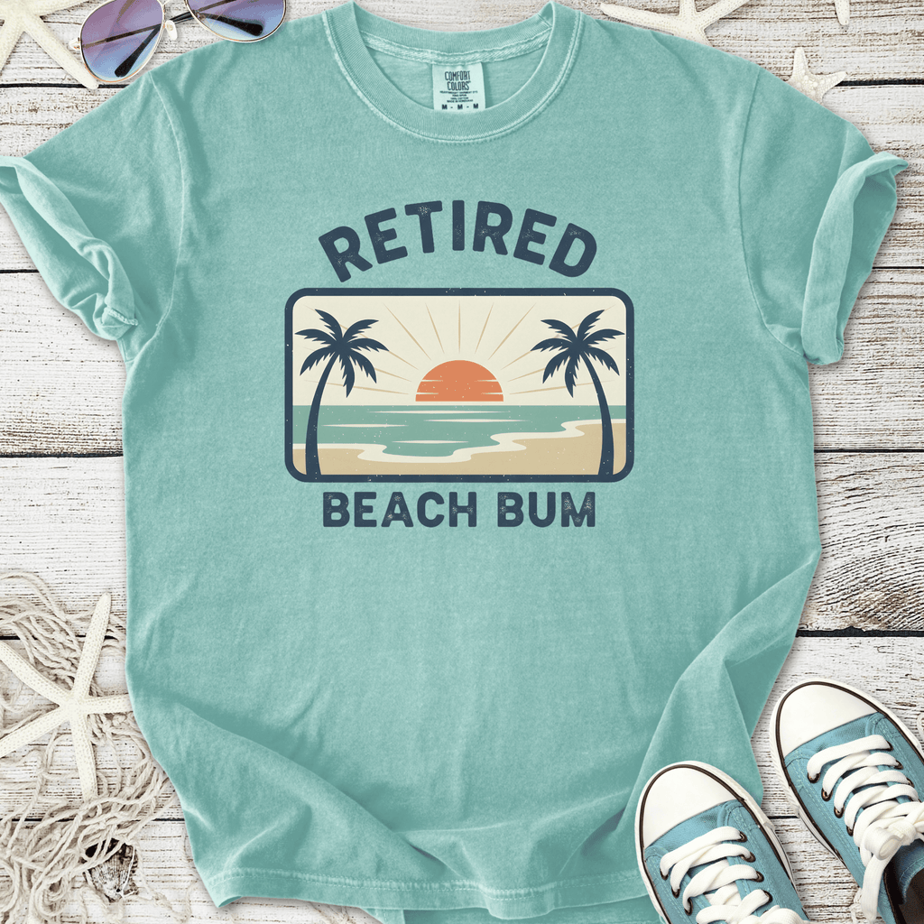 Mint green retired beach bum t-shirt with sunset and palm tree graphic for casual summer wear.