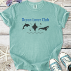 Light teal t-shirt with 'Ocean Lover Club' design featuring dolphins, a manta ray, and a whale.