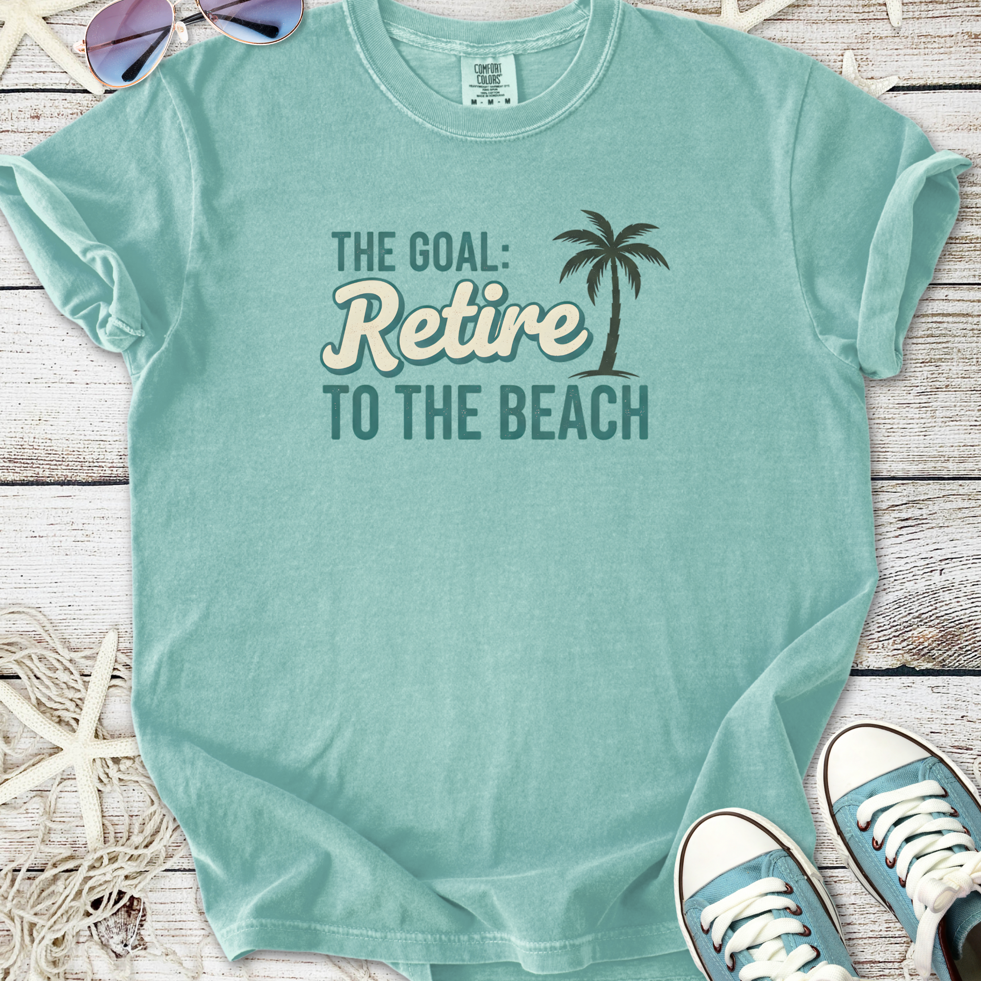 Light blue cotton t-shirt with 'Retire to the Beach' graphic, perfect for beach lovers and casual wear.