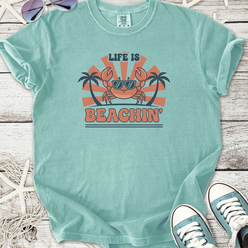 Light teal t-shirt featuring a crab graphic with sunglasses and 'Life is Beachin' text, cotton material.